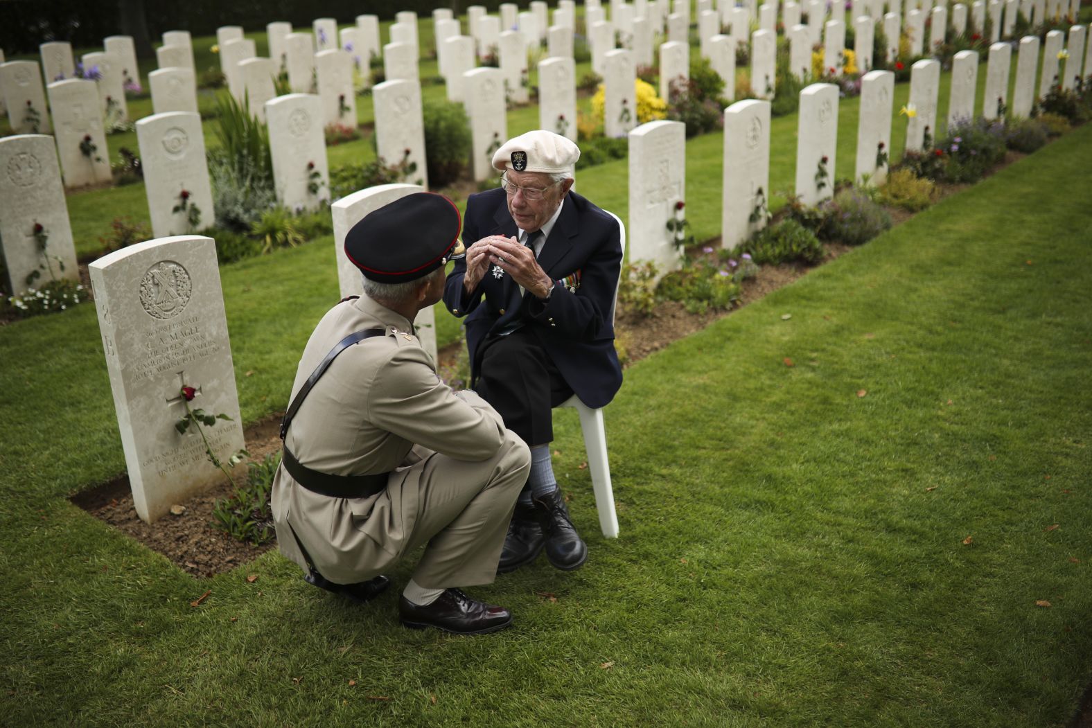 A World War II veteran talks to a soldier at the end of a ceremony to mark the 75th anniversary of D-Day at the Bayeux War Cemetery in Bayeux.