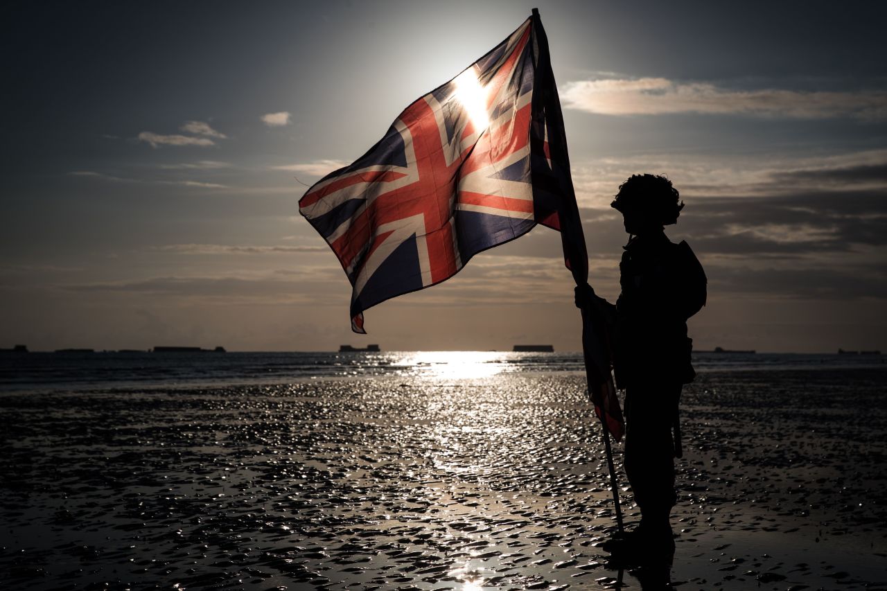 A soldier holds an English flag on the beach of Arromanches to mark the 75th anniversary of the World War II Allied landings in Normandy.