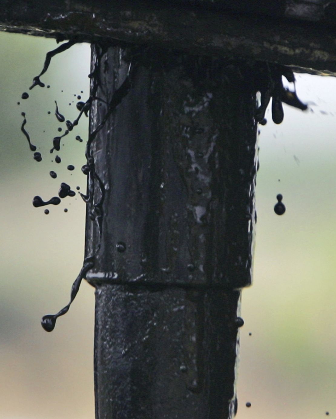 Oil drips out as workers lay pipe into an oil well in Talpa, Texas.