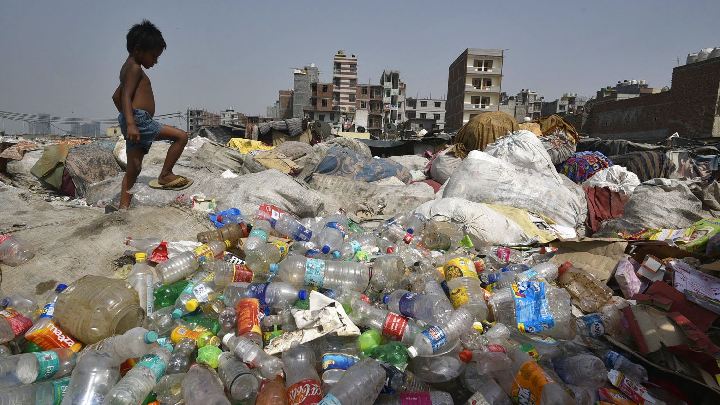 A boy looks for recyclable material as piles of plastic lie on the bank of Yamuna in New Delhi, India.  