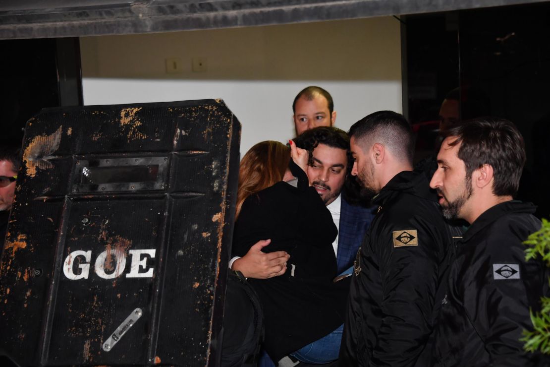 Najila Trindade is carried by her lawyer Danilo Garcia de Andrade to a police car.