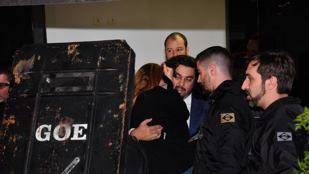 Najila Trindade is carried by her lawyer Danilo Garcia de Andrade to a police car.