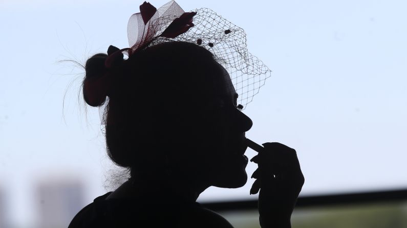 Joanne Principe touches up her lipstick while watching an early race before the running of the Belmont Stakes.