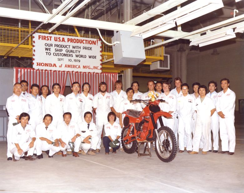Associates pose alongside the CR250R motorcycle model at Honda's first motorcycle plant. 