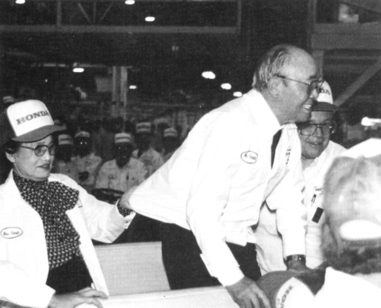 Soichiro Honda's wife clutches his shirt to prevent him falling while he bows and greets associates at the Marysville plant. 