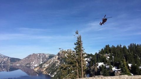 A helicopter flies over Crater Lake.