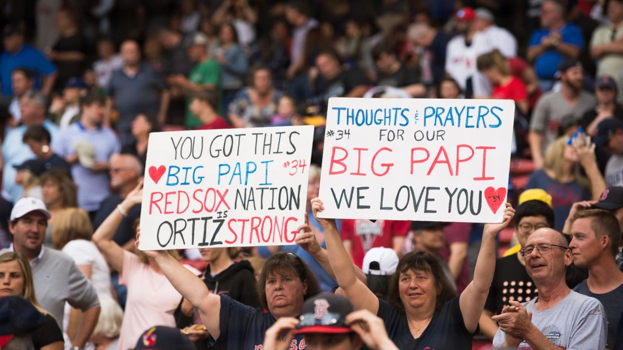 Fans hold up signs showing support for former Red Sox player David Ortiz before the start of the game against the Texas Rangers at Fenway Park on Monday.