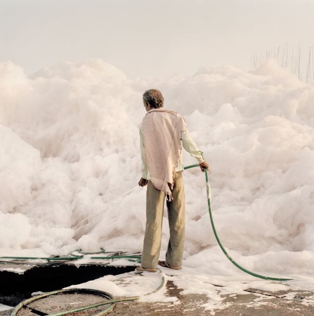 A worker hoses down foam created by chemical waste.<br />