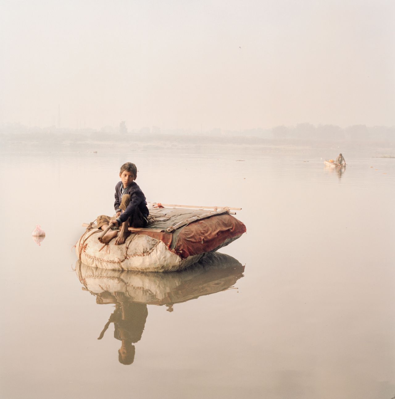 A boy fishes for coins with a string and a magnet along the Yamuna River, a tributary of the Ganges.