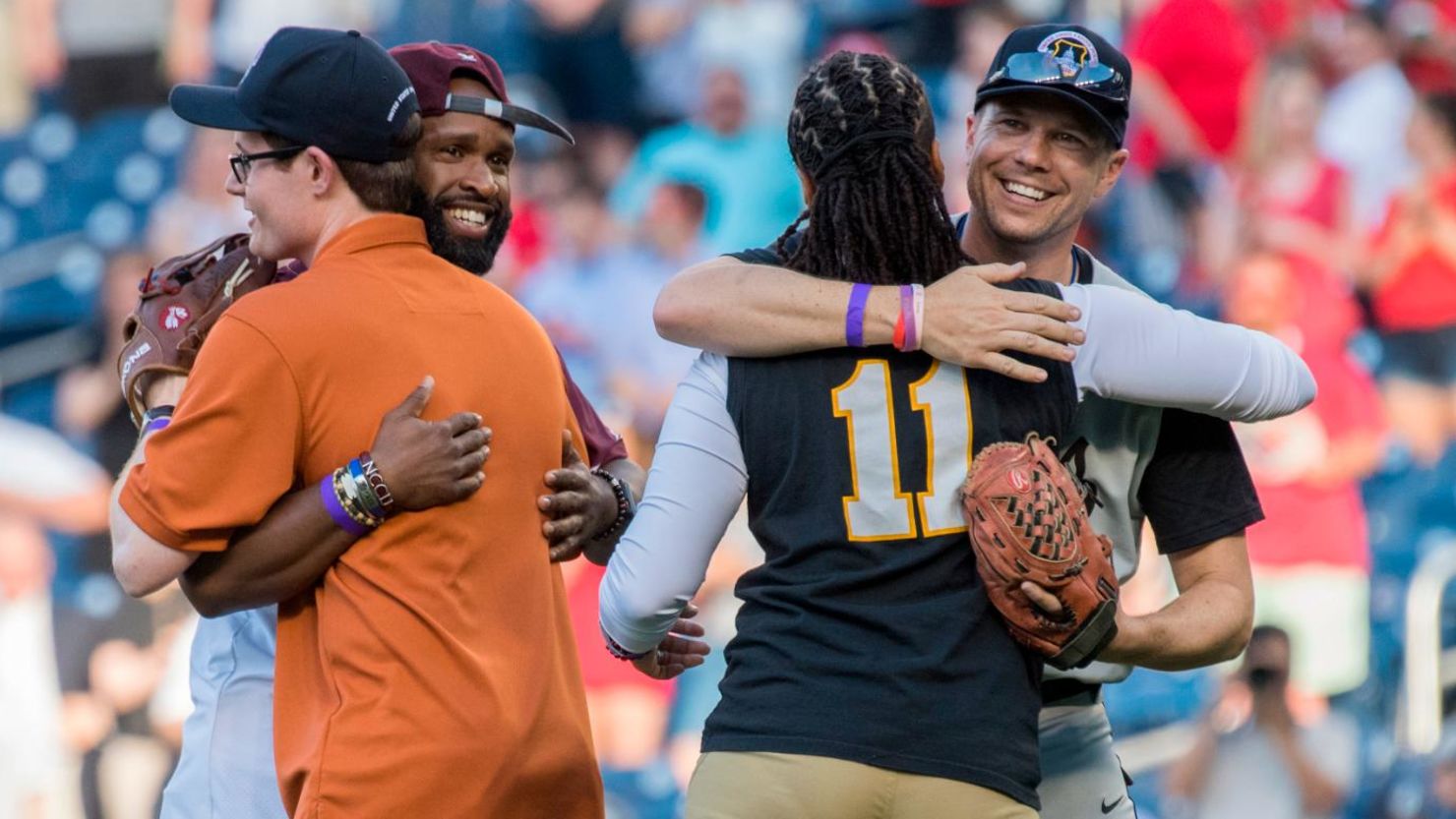 Matt Mika, far right, and Zack Barth, orange shirt, who were wounded in the GOP baseball practice shooting last year, hug US Capitol Police Special Agents David Bailey and Crystal Griner, during the 57th annual Congressional Baseball Game at Nationals Park on June 14, 2018. Bailey and Griner helped neutralize the shooter in 2017. (Photo By Tom Williams/CQ Roll Call)