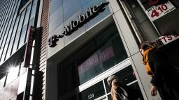 Pedestrians pass in front of a T-Mobile US Inc. store in New York, U.S. on Monday, April 30, 2018. Sprint Corp. suffered its worst stock decline in almost six months, rocked by fears that a proposed $26.5 billion takeover by T-Mobile US Inc. will get rejected by antitrust enforcers. Photographer: Jeenah Moon/Bloomberg via Getty Images