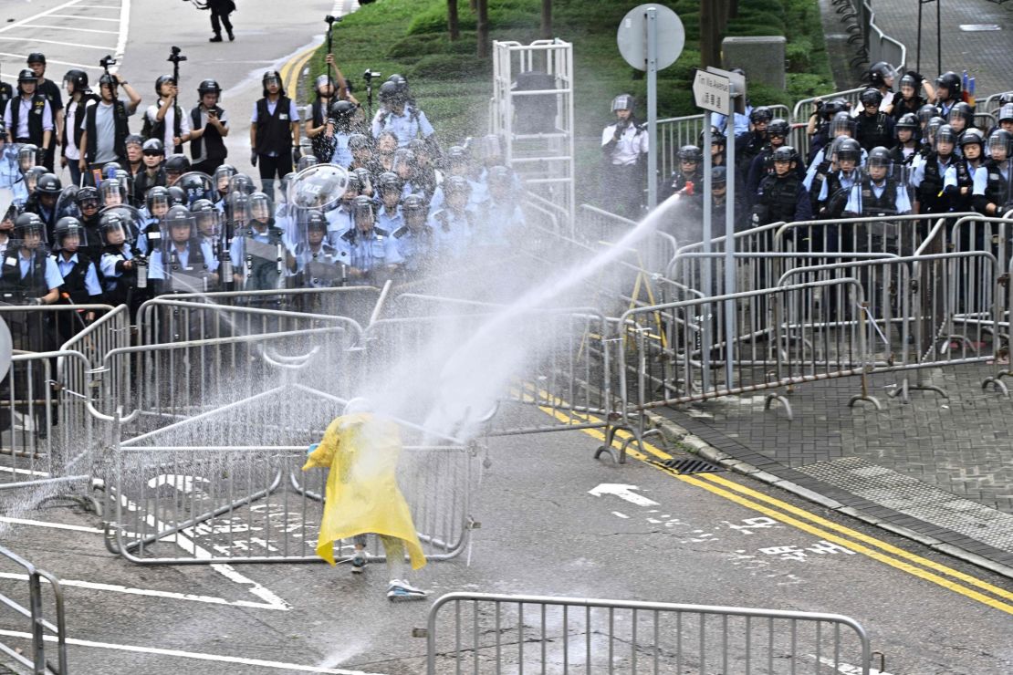 Police officers use a water canon on a lone protester near the government headquarters in Hong Kong on June 12, 2019.