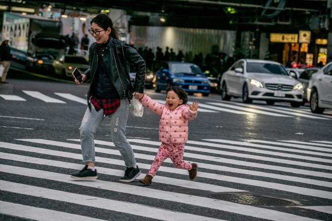 <strong>Starting young: </strong>A mother and her daughter make their way across the intersection during a break in traffic.
