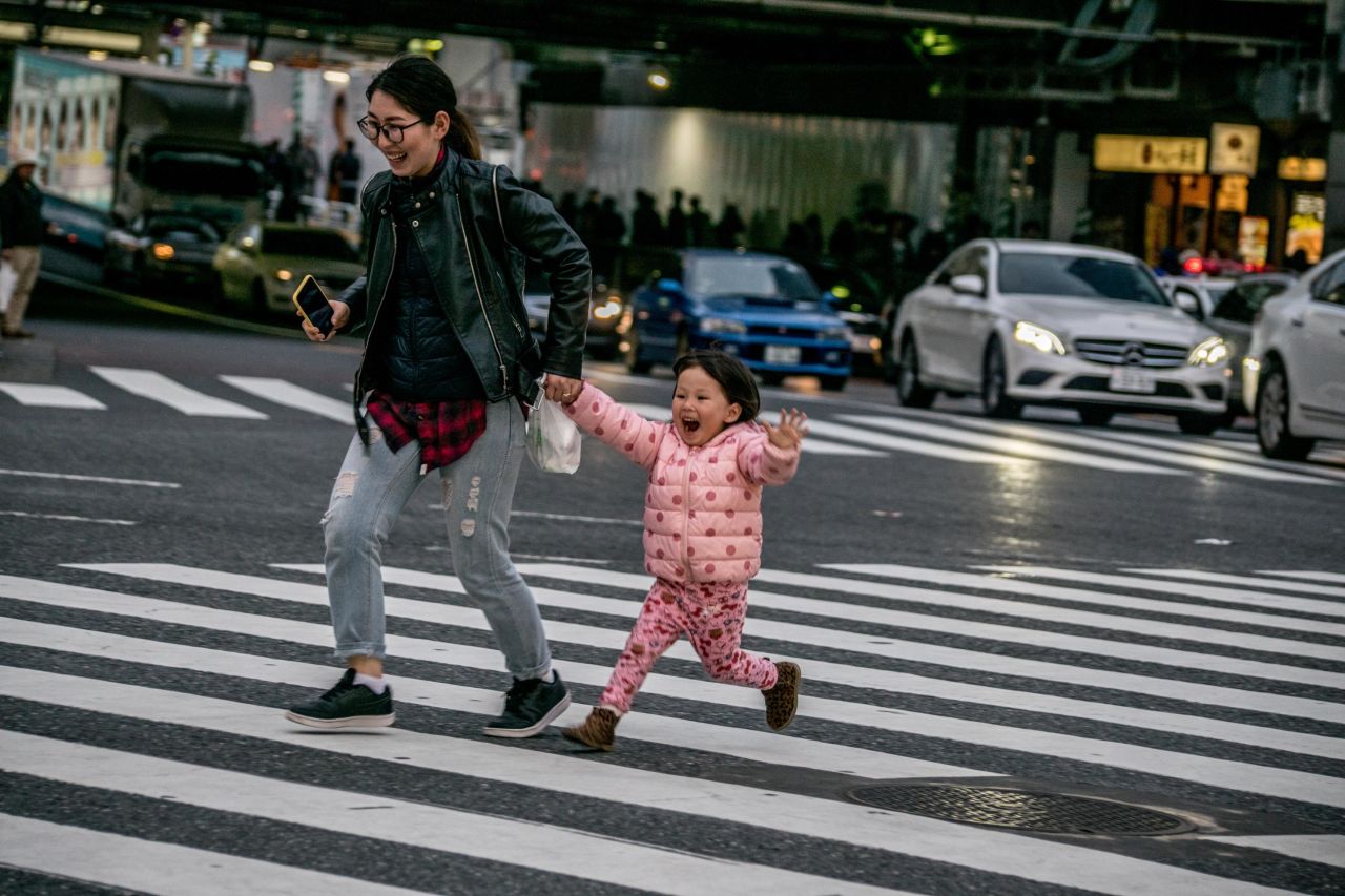 <strong>Starting young: </strong>A mother and her daughter make their way across the intersection during a break in traffic.