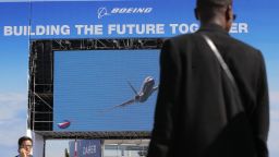 Visitors walk past a giant screen of Boeing as as the lading of a 737 Max is shown at Paris Air Show, in Le Bourget, east of Paris, France, Monday, June 17, 2019. The world's aviation elite are gathering at the Paris Air Show with safety concerns on many minds after two crashes of the popular Boeing 737 Max. (AP Photo/Michel Euler)