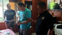In this June 15, 2019, photo released by Crime Suppression Division, Italian Francesco Galdeli, center, is arrested by Thai police officers at a house in Chonburi. Thai police said they have arrested the Italian man wanted in his home country after fleeing a jail sentence handed down for fraudulently using the name of actor George Clooney to lure people into investing in a bogus clothing company. (Crime Suppression Division of Thailand via AP)