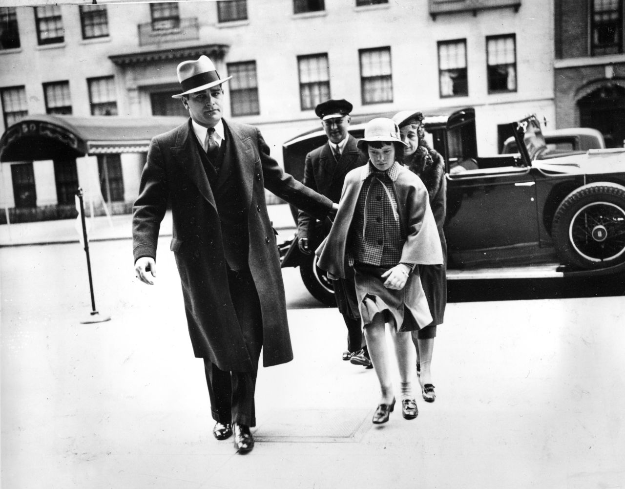 Vanderbilt is accompanied by a bodyguard, nurse and chauffeur as she enters her mother's Manhattan home for an Easter weekend visit in 1935. Vanderbilt was the focus of media attention at an early age, dubbed "the poor little rich girl" amid an intense custody battle between her mother and her father's enormously wealthy sister, Gertrude Vanderbilt Whitney. Her aunt prevailed in court proceedings.