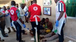 EDITORS NOTE: Graphic content / Red Cross officials attend to victims of a triple suicide bombing, which occured outside a hall in Konduga, 38 kilometres (24 miles) from the Borno state capital Maiduguri, northeast Nigeria, on June 17, 2019. - Thirty people were killed late on June 16 in a triple suicide bombing in northeast Nigeria, emergency services reported, in an attack bearing the hallmarks of the Boko Haram jihadist group. Three bombers detonated their explosives outside a hall in Konduga, 38 kilometres (24 miles) from the Borno state capital Maiduguri, where football fans were watching a match on TV. (Photo by Audu Ali MARTE / AFP)        (Photo credit should read AUDU ALI MARTE/AFP/Getty Images)