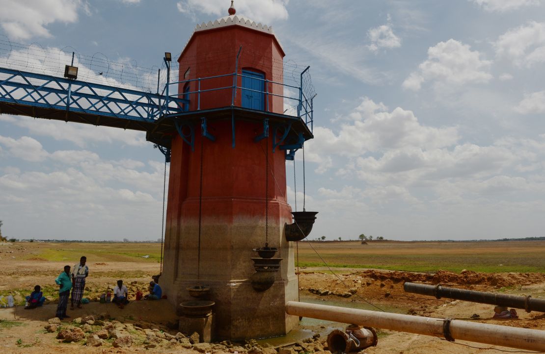 Men sit in the shade of a measuring tower at the dried-out Puzhal reservoir on the outskirts of Chennai on Friday.