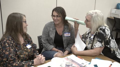 Peggy Oyer (right) takes part in a listening exercise that illustrates how someone hearing voices while experiencing a psychotic episode might feel. 