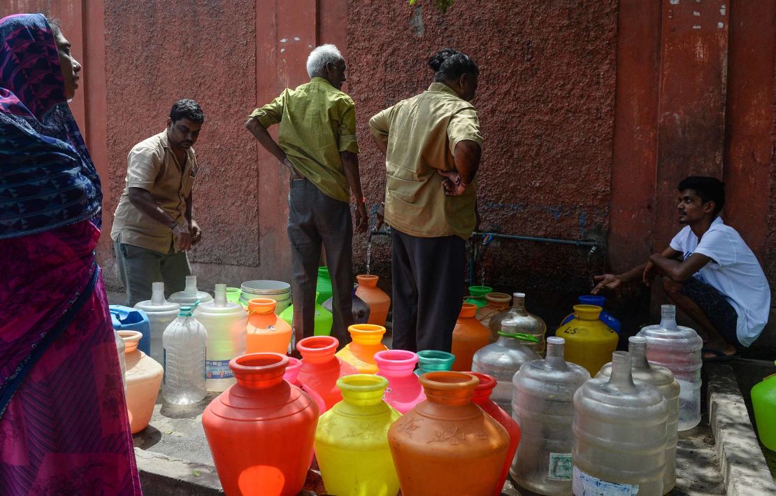 Residents stand around with plastic pots filled with drinking water at a distribution point in Chennai on June 19, 2019.