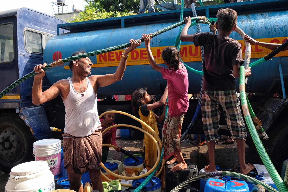 Indian residents use hoses to collect drinking water from a tanker in Sanjay, New Delhi.