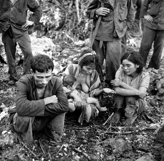 A civilian family squats on the ground, surrounded by US Marines after the battle between US and Japanese forces for control of Saipan in July 1944.
