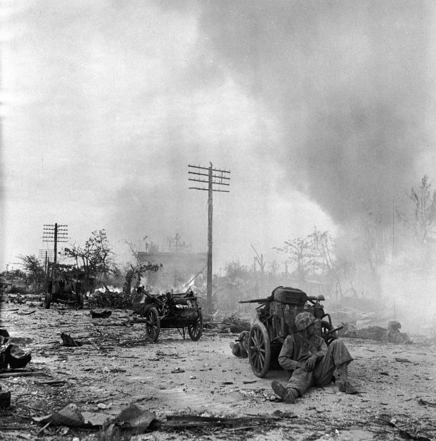 A US Marine rests behind a cart on a rubble strewn street during the battle to take Saipan from occupying Japanese forces on July 9, 1944.