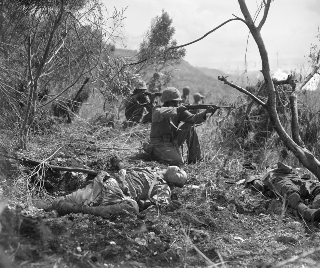 With dead Japanese soldiers nearby, Marines aim at the enemy during the US invasion of Saipan.