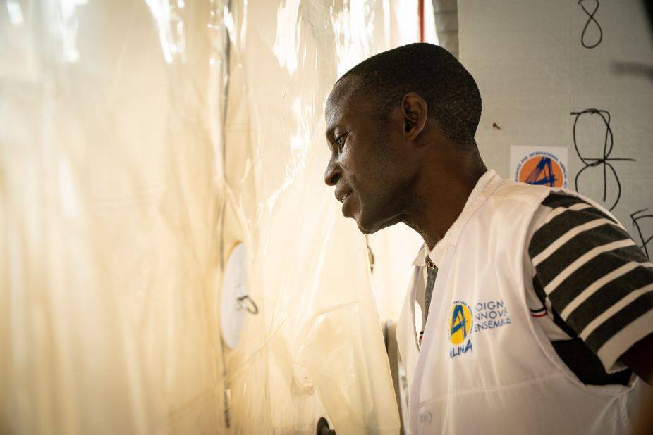 Dr. Camara Modet of Alima, a French medical non-governmental organization, looks in on his Ebola patient through the walls of the CUBE. It's a biosecure emergency room  designed in response to the treatment centers' lack of adaptability. The innovative new isolation system allows doctors and families to interact through a barrier without wearing protective gear. "They can see with their own eyes that we are caring for their loved ones," says Modet.