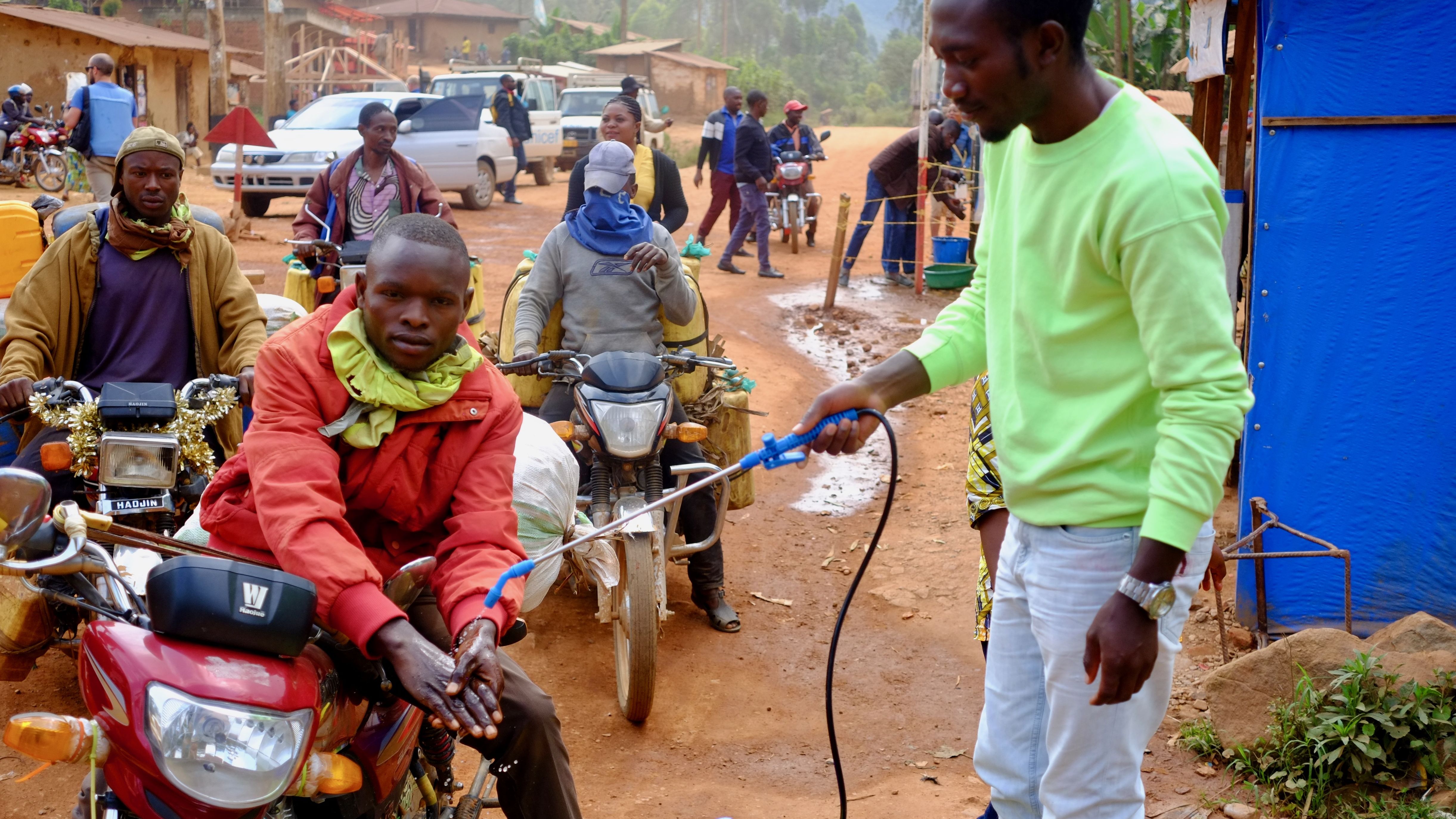 A motorcycle taxi driver gets his hands washed with a chlorine solution at a checkpoint between Beni and Butembo in estern Democratic Republic of Congo.