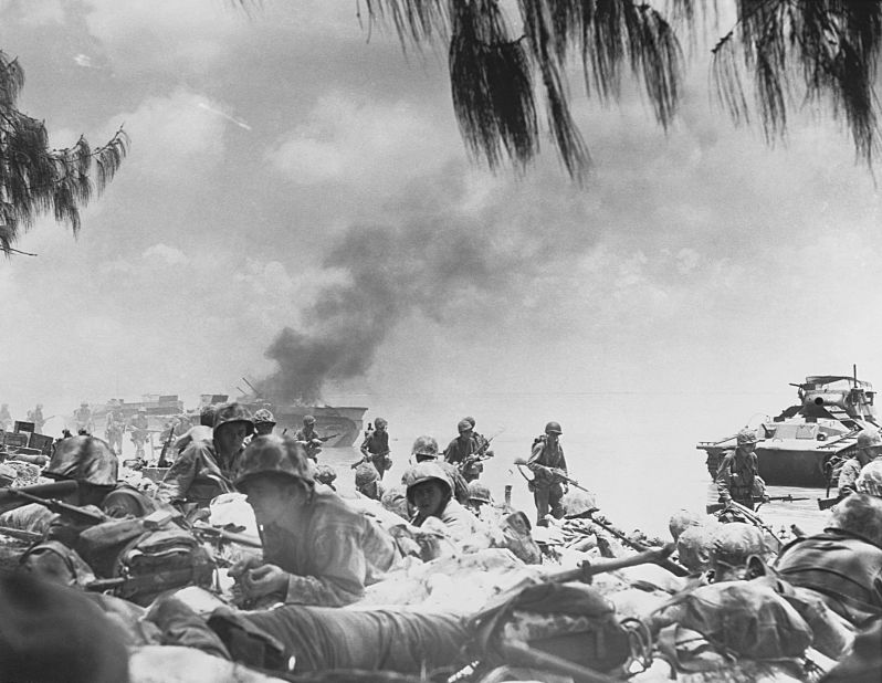 US Marines crawl on the beach to avoid Japanese gunfire after landing on Saipan.