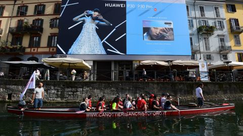 Tourists on a boat pass by a Huawei billboard on the Naviglio canal, south of Milan.