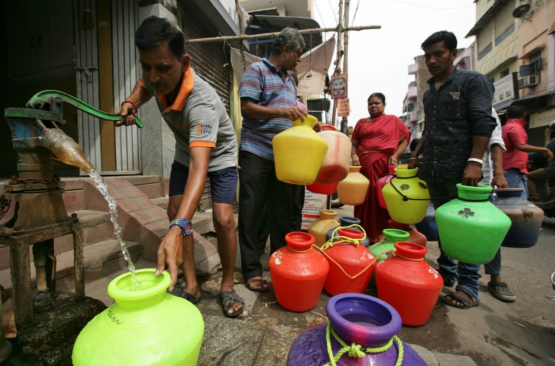 A man uses a hand-pump to fill a container with drinking water as others wait in line in Chennai, India, on June 17, 2019. 