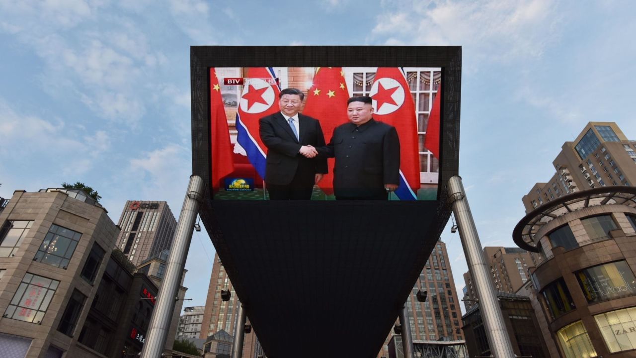 News footage of  Xi, left, being greeted in Pyongyang by Kim is shown on a large screen outside a shopping mall in Beijing.