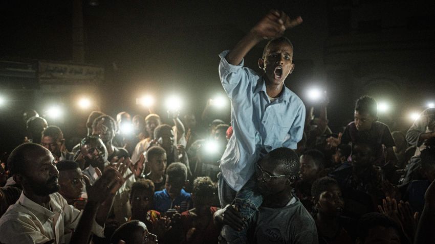 People chant slogans as a young man recites a poem, illuminated by mobile phones, before the opposition's direct dialog with people in Khartoum on June 19, 2019. - People chanted slogans including "revolution" and "civil" as the young man recited a poem about revolution. (Photo by Yasuyoshi CHIBA / AFP)        (Photo credit should read YASUYOSHI CHIBA/AFP/Getty Images)