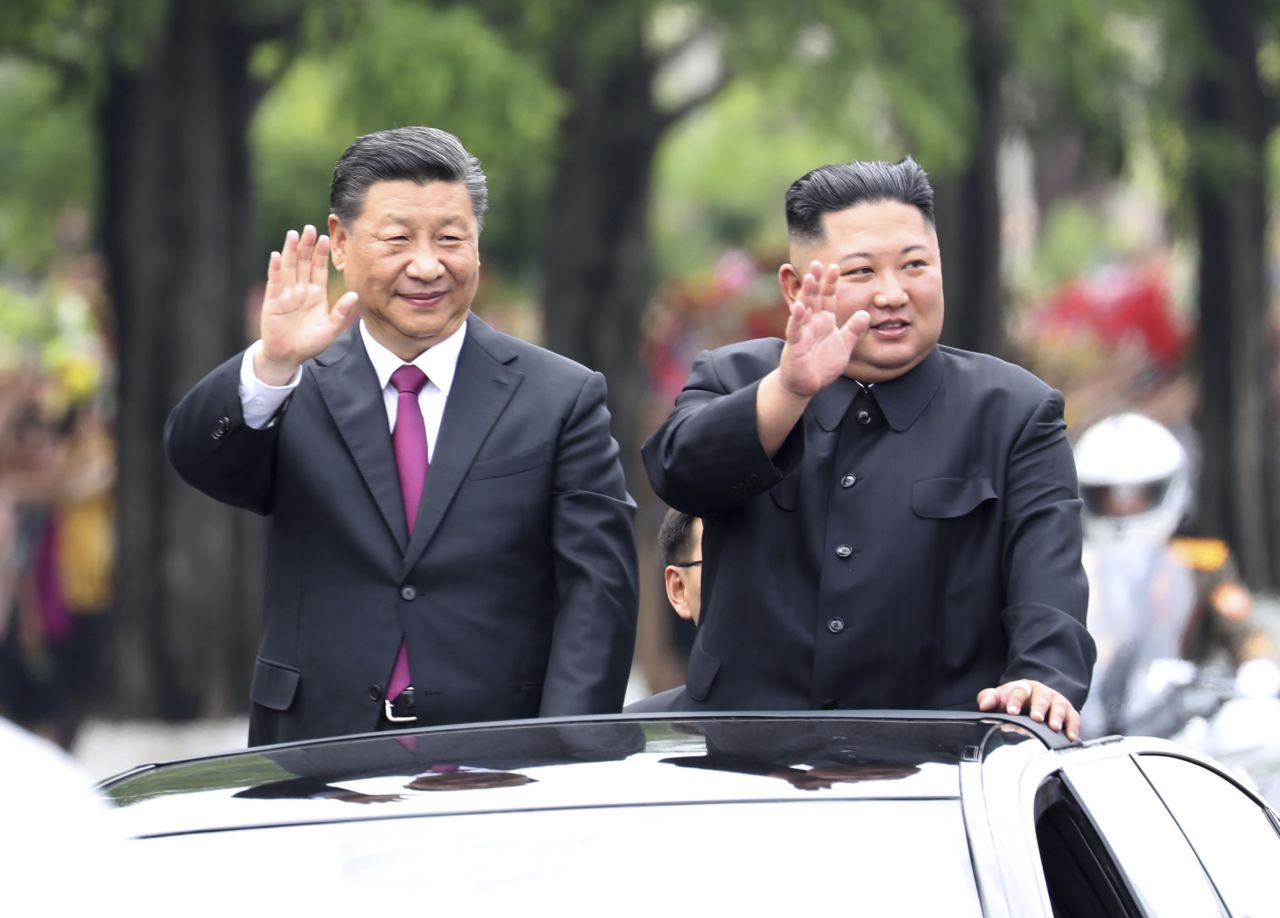 Xi and Kim wave from an open top limousine as they travel along a street in Pyongyang, North Korea.