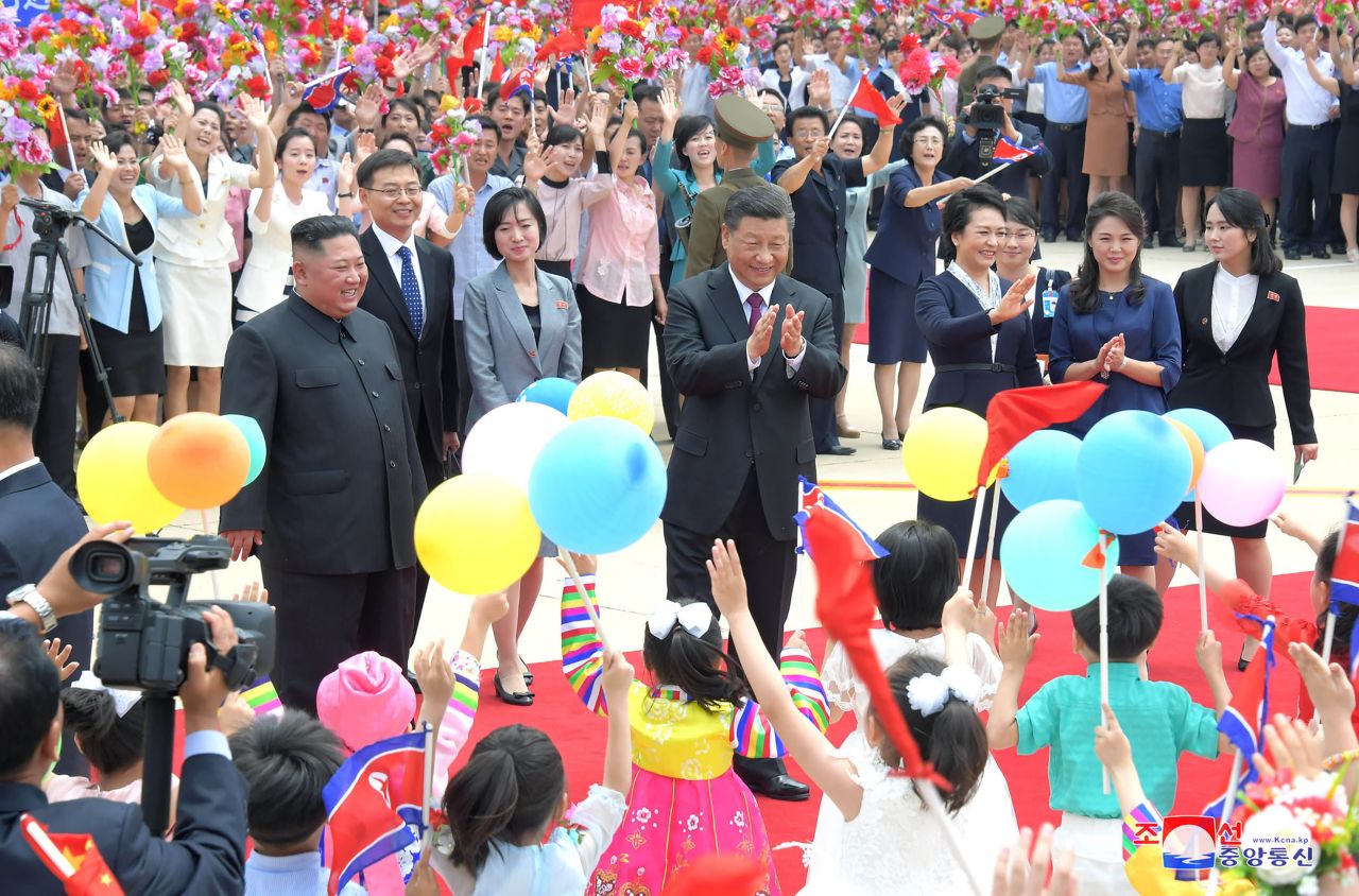 Xi, center, is welcomed by North Korean children at Pyongyang International Airport.