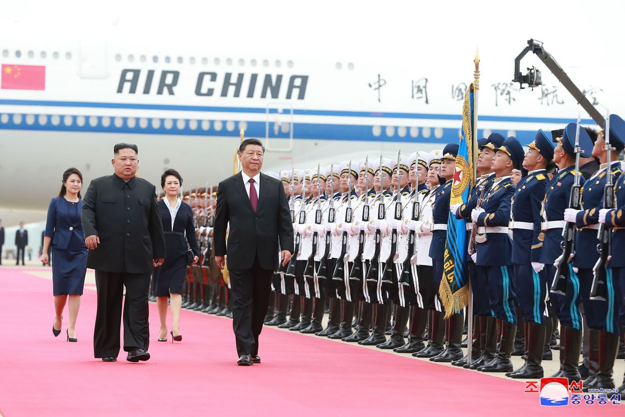 Kim and Xi walk past the honor guard at Pyongyang International Airport in Pyongyang.