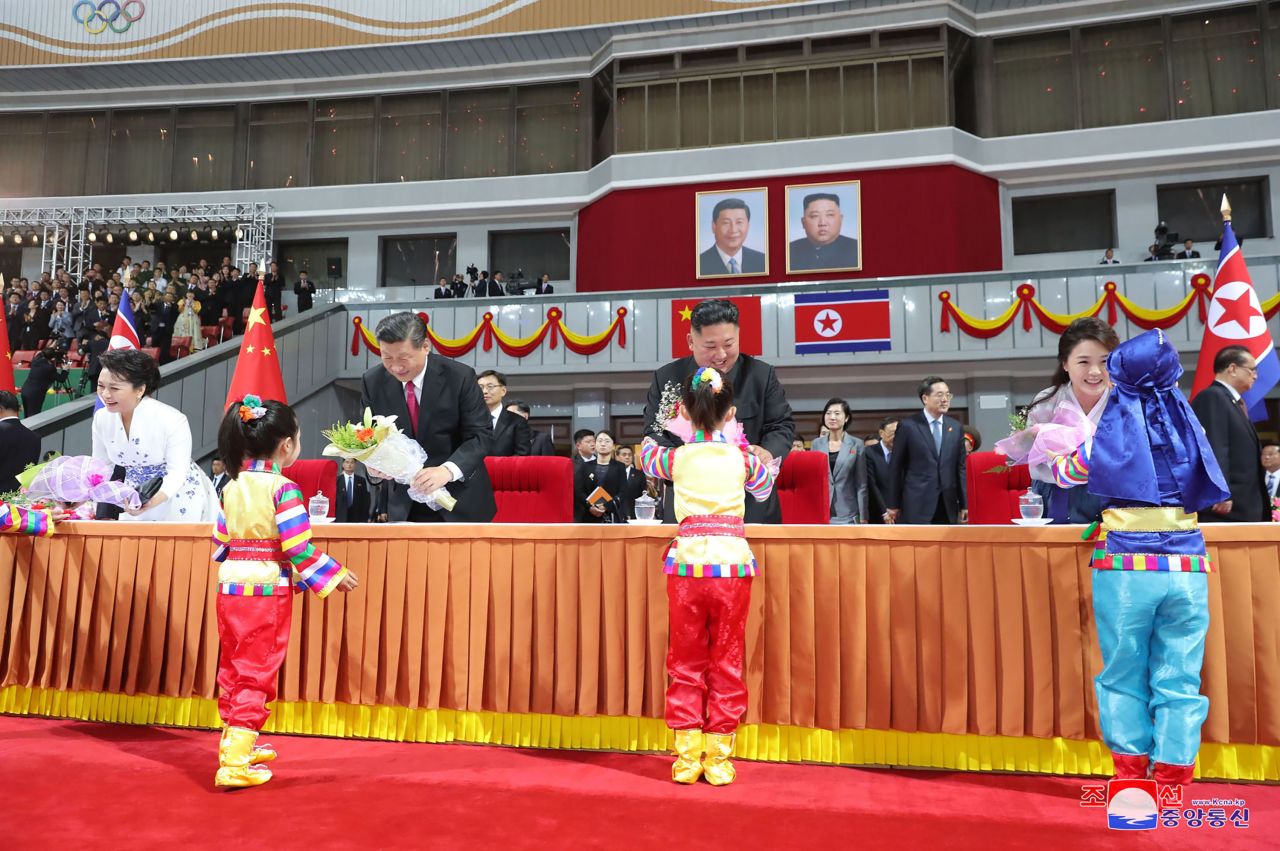 Kim, center right, and his wife Ri Sol Ju, right,Xi Jinping, center left, and his wife Peng Liyuan receive flowers from children during a mass gymnastic performance at the May Day Stadium in Pyongyang, North Korea.