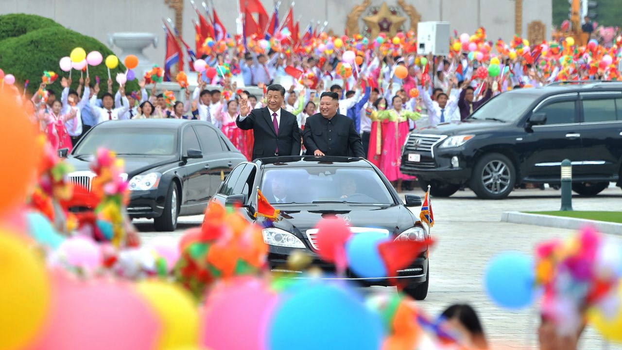 North Korean leader Kim Jong Un, right, and Chinese President Xi Jinping, left, acknowledge people on a street in Pyongyang, North Korea.