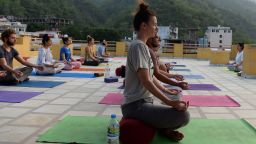 This picture taken on June 19, 2018, shows people practising yoga on a terrace at the Anand Prakash yoga ashram in Rishikesh in India's Uttarakhand state. - International Yoga Day, which is being celebrated on June 21, was proposed by Indian Prime Minister Narendra Modi in 2014 to the UN General Assembly and adopted unanimously. This year tens of thousands will take part worldwide. (Photo by Sajjad HUSSAIN / AFP) / To go with: 'LIFESTYLE-INDIA-RELIGION-YOGA-HISTORY'; feature by Simon STURDEE        (Photo credit should read SAJJAD HUSSAIN/AFP/Getty Images)