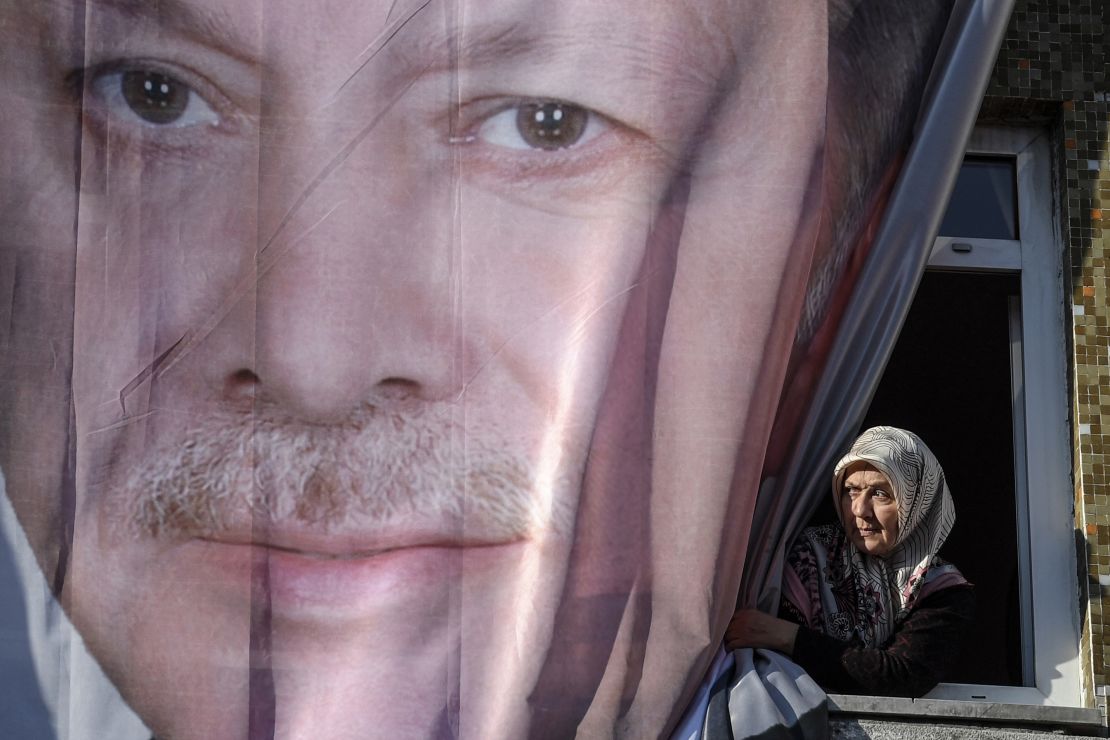 A woman peers out from behind a giant poster of Erdoğan during a March rally in Kasımpaşa.