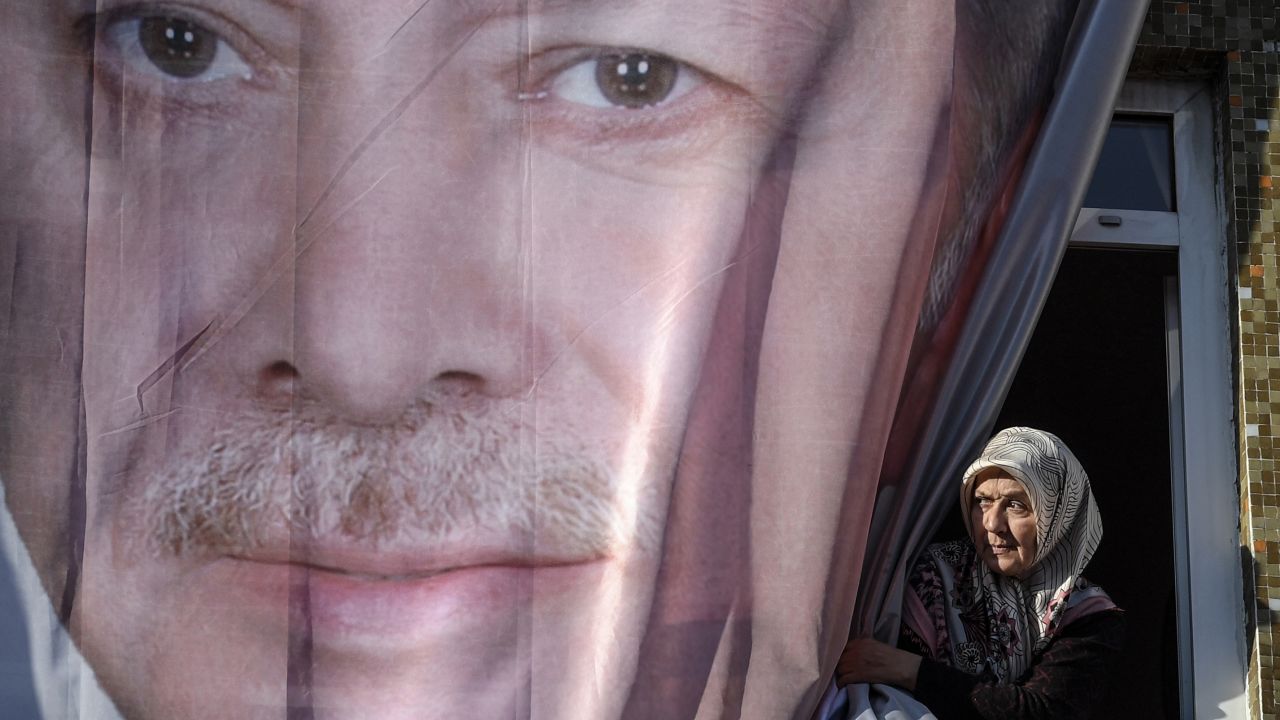 A woman peers out from behind a giant poster of Erdoğan during a March rally in Kasımpaşa.
