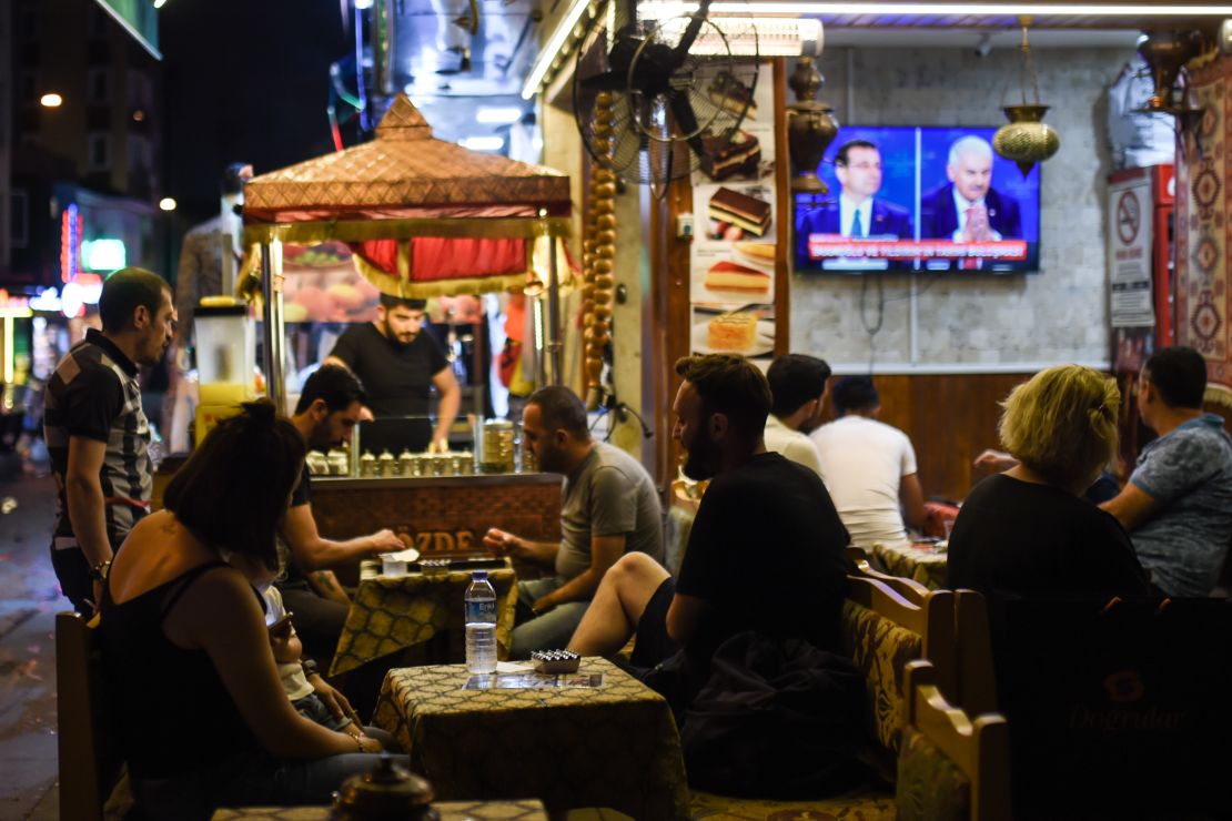 At an Istanbul café, people watch a live TV debate between Istanbul's main mayoral candidates.