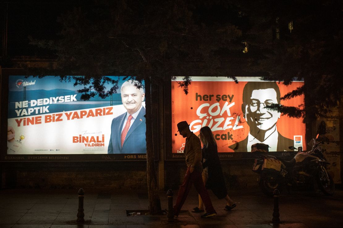 People walk past Yıldırım and İmamoğlu election posters amid campaigning for the rerun.