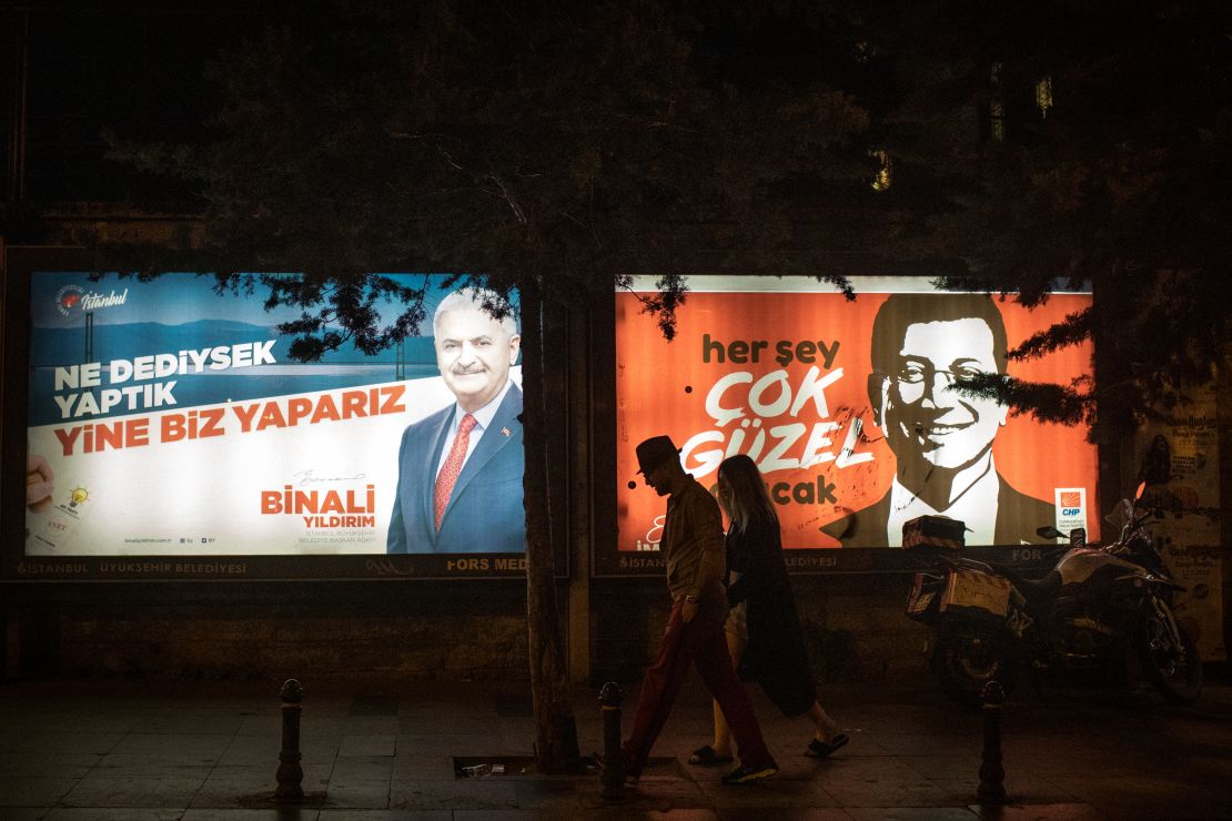 People walk past Y?ld?r?m and ?mamo?lu election posters amid campaigning for the rerun.