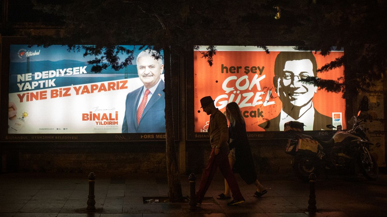 People walk past Yıldırım and İmamoğlu election posters amid campaigning for the rerun.
