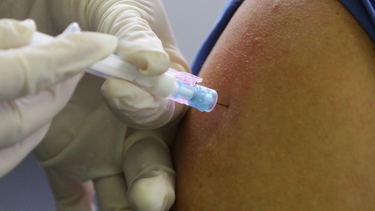 A doctor injects a flu vaccination.