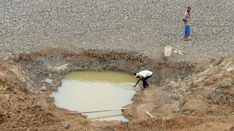 A worker collects water at the dried-out Puzhal Reservoir on the outskirts of Chennai, India, on June 20.